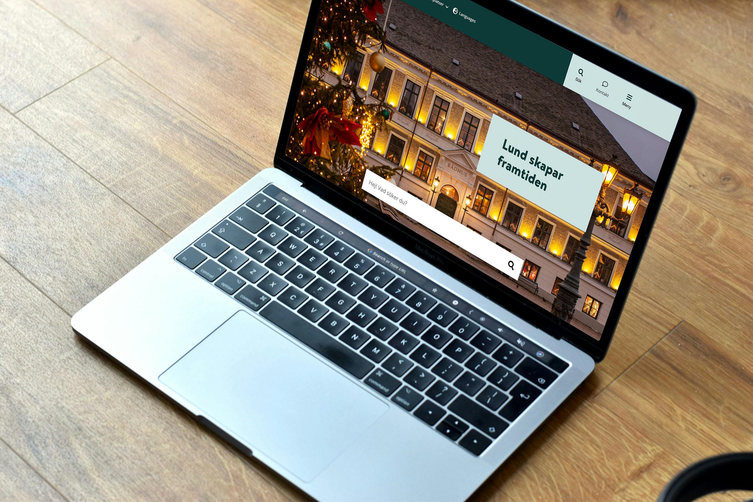 Lund kommuns nya webbplats utvecklad av Consid, i en MacBook Pro på ett underlag i trä