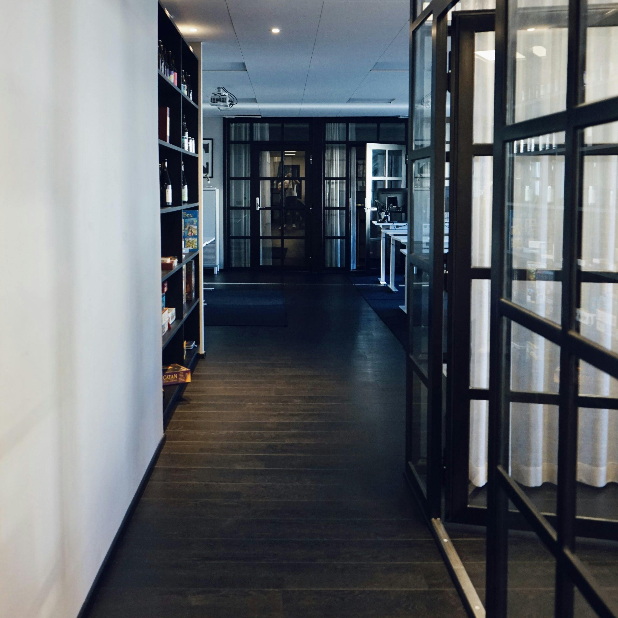 Korridor med glasdörrar och hyllvägg på Consids kontor i Göteborg.