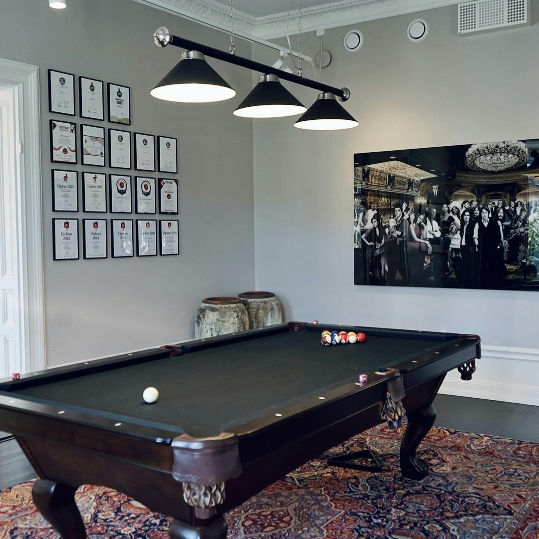 Pool table with lamp above and photo art and paintings in the background at Consid's office in Gävle.
