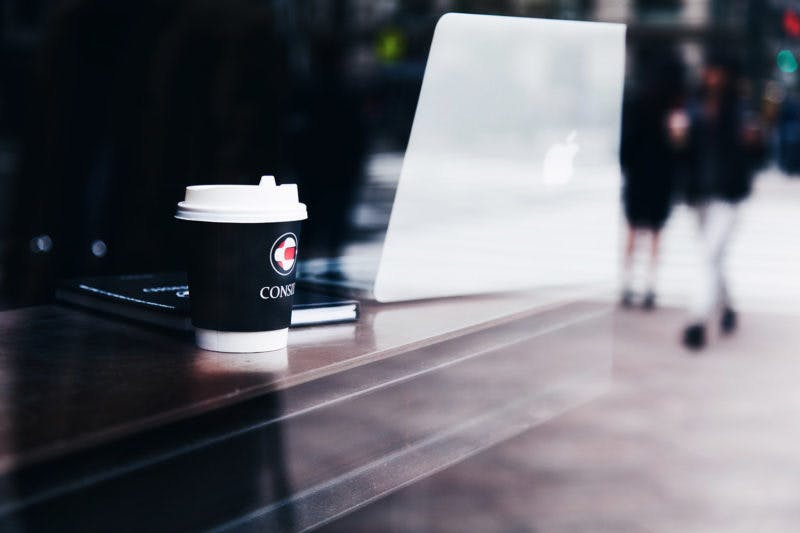 Consid kaffemugg och laptop på ett kafé i skyltfönstret