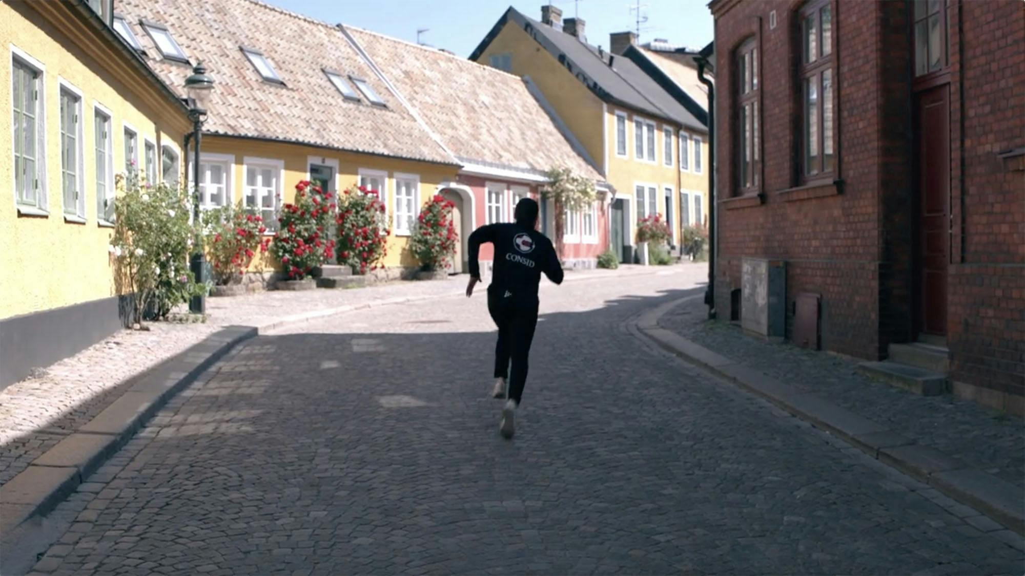 En kvinna som springer ned längst Lunds kullerstensgator.