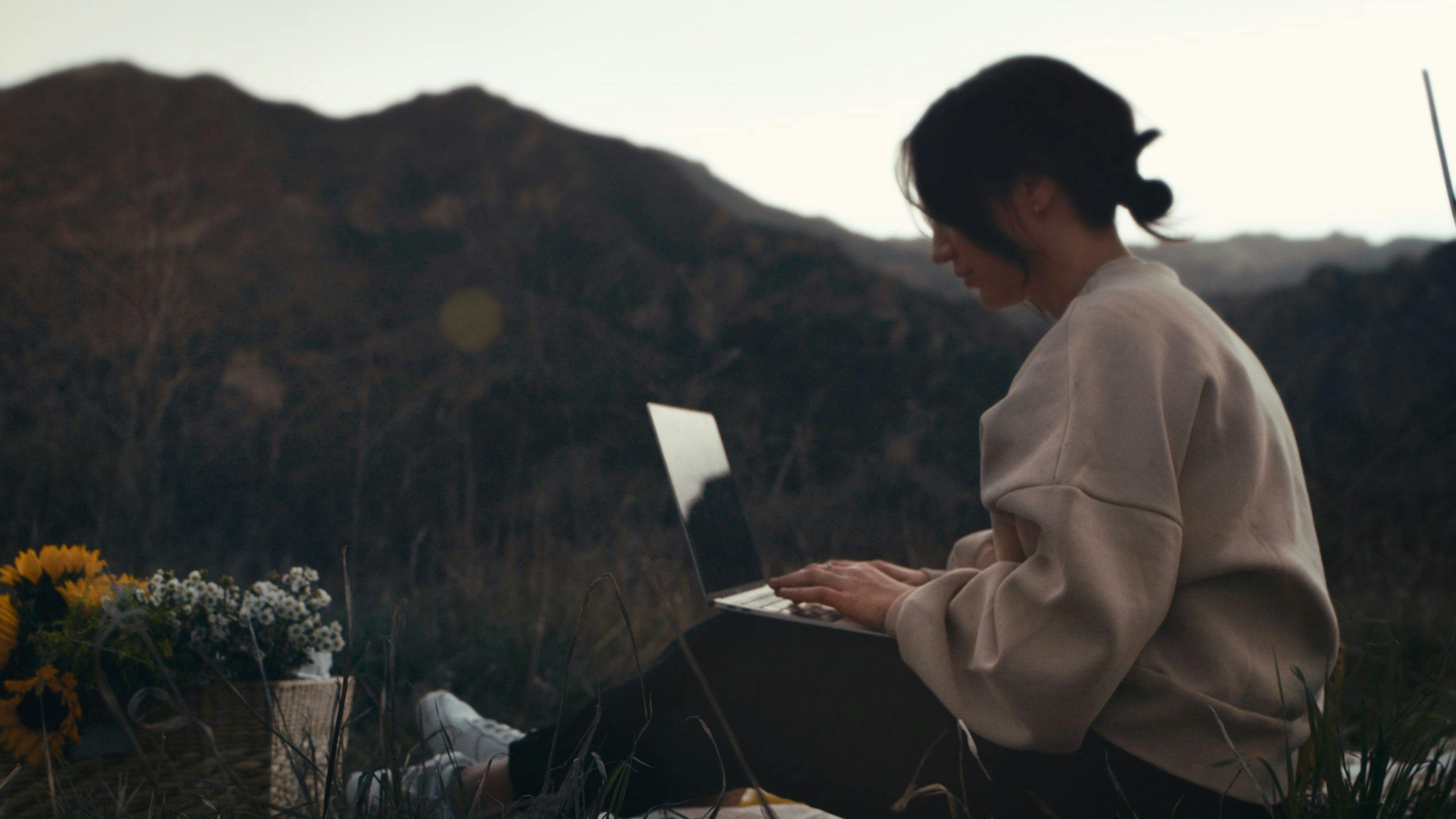 Woman sitting in the mountains with her laptop in her knees