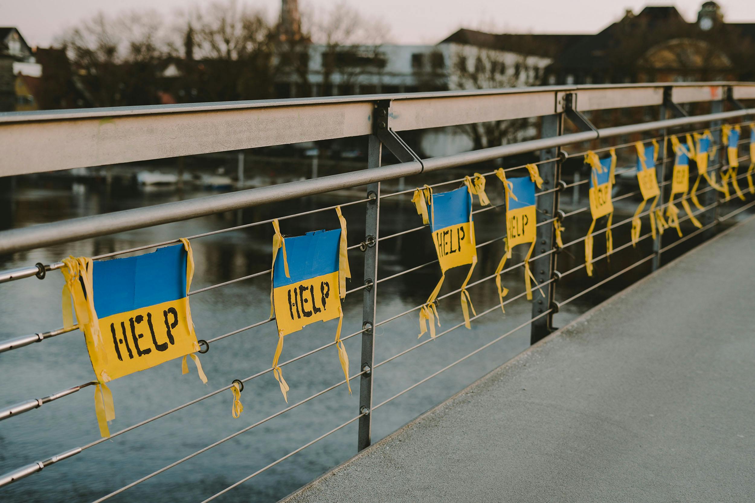 Flera mindre ukrainska flaggor med texten "help" på en bro
