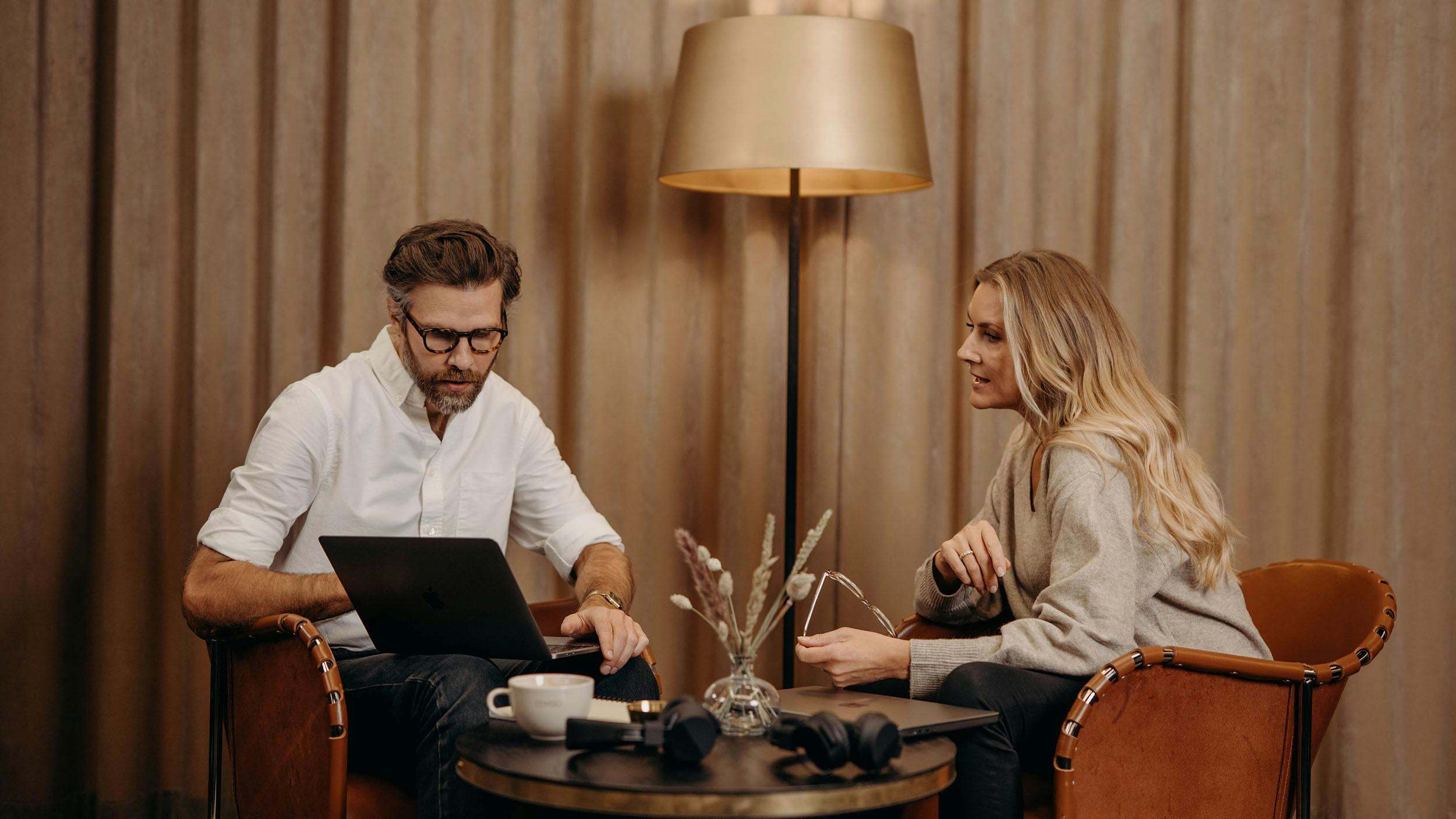 Två personer som sitter vid ett bord och tittar på en dator.