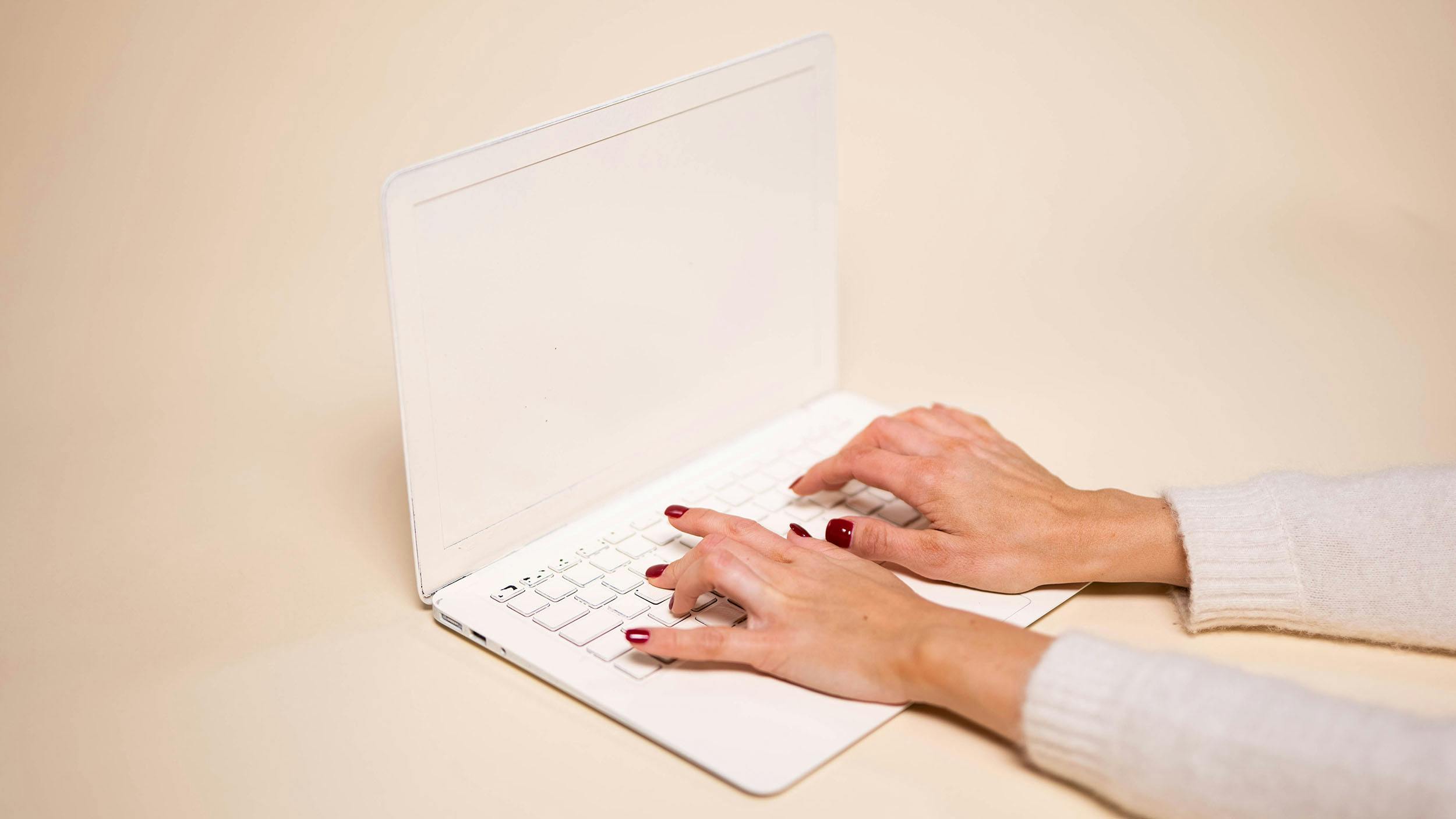 En vitmålad laptop som används av en person.